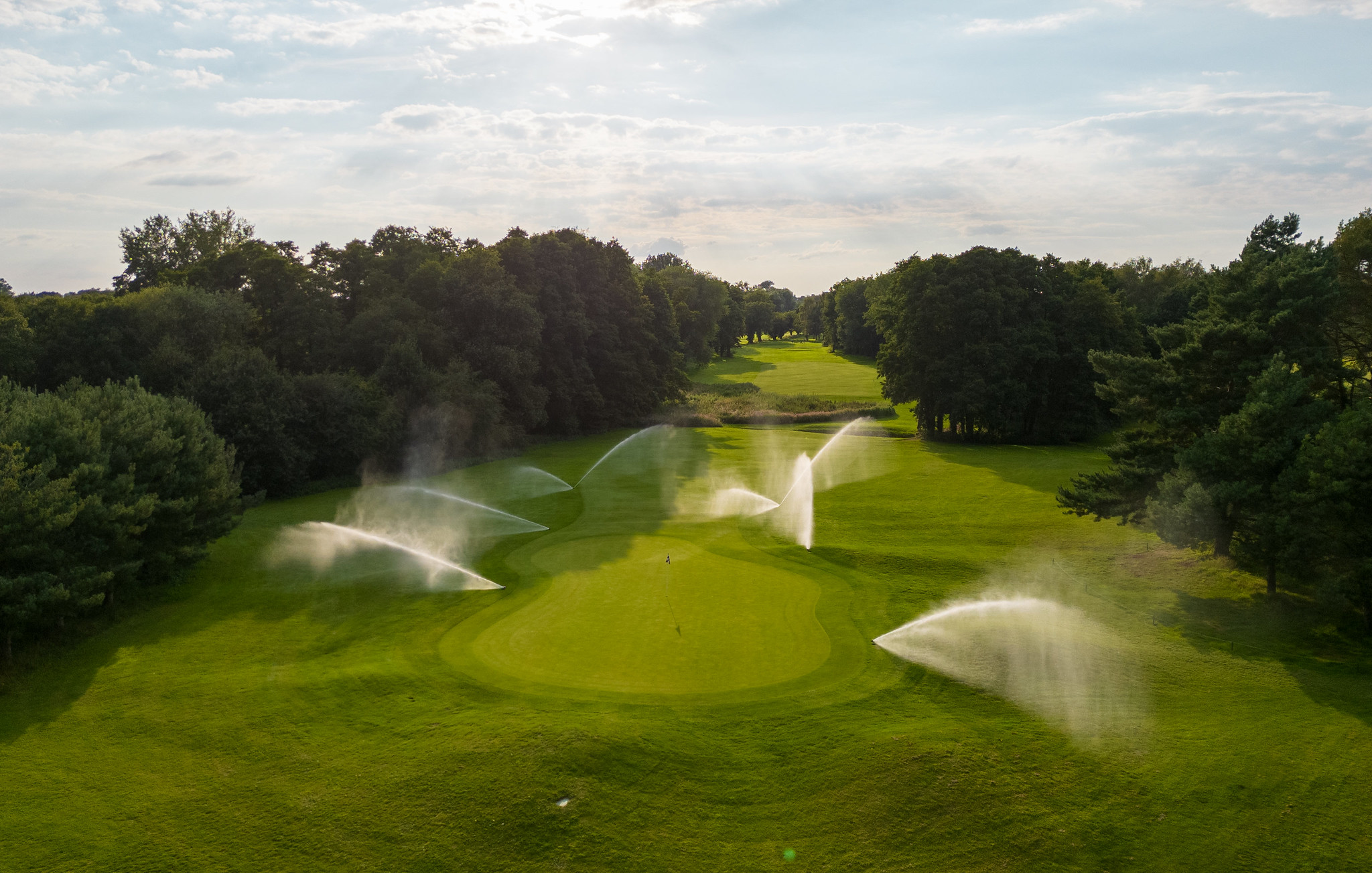 Aerial shot of a golf course with multiple active sprinklers