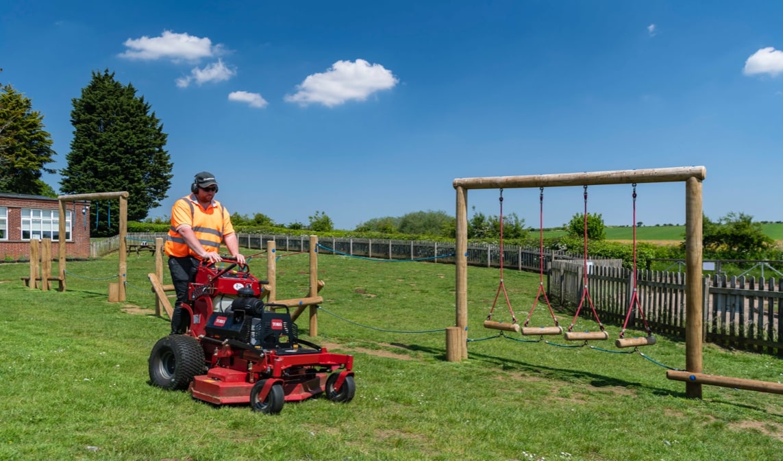 A Toro mower being used to cut a playground.