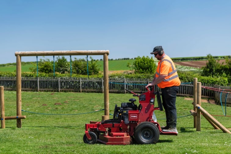 Toro GrandStand mower being used on a playground.