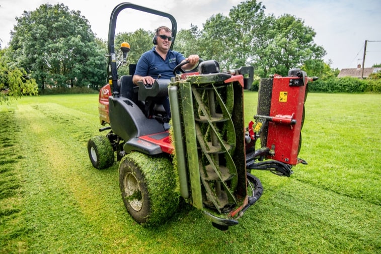 CGM Group's Neil Green driving a Toro LT3340 across recently cut grass with the blades up.